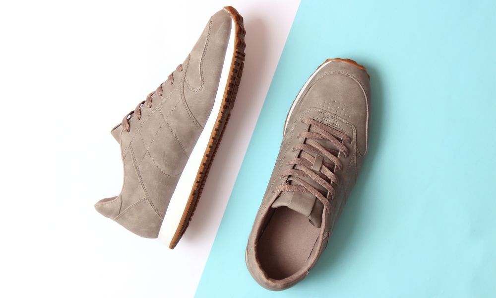 Top-down view of tan suede sneakers on a split white and light blue background.